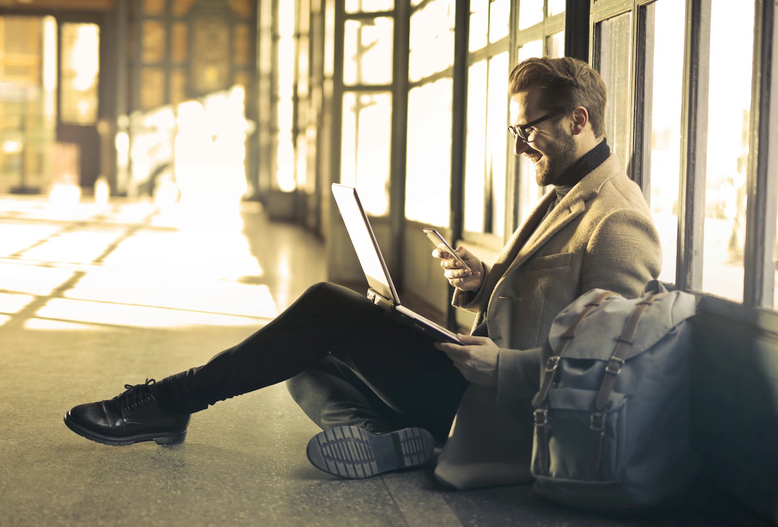 A business traveller working on a laptop and phone by a window