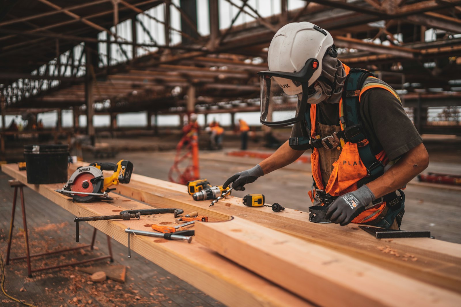 A tradesman in a hard hat and hi-vis vest working with a power tool
