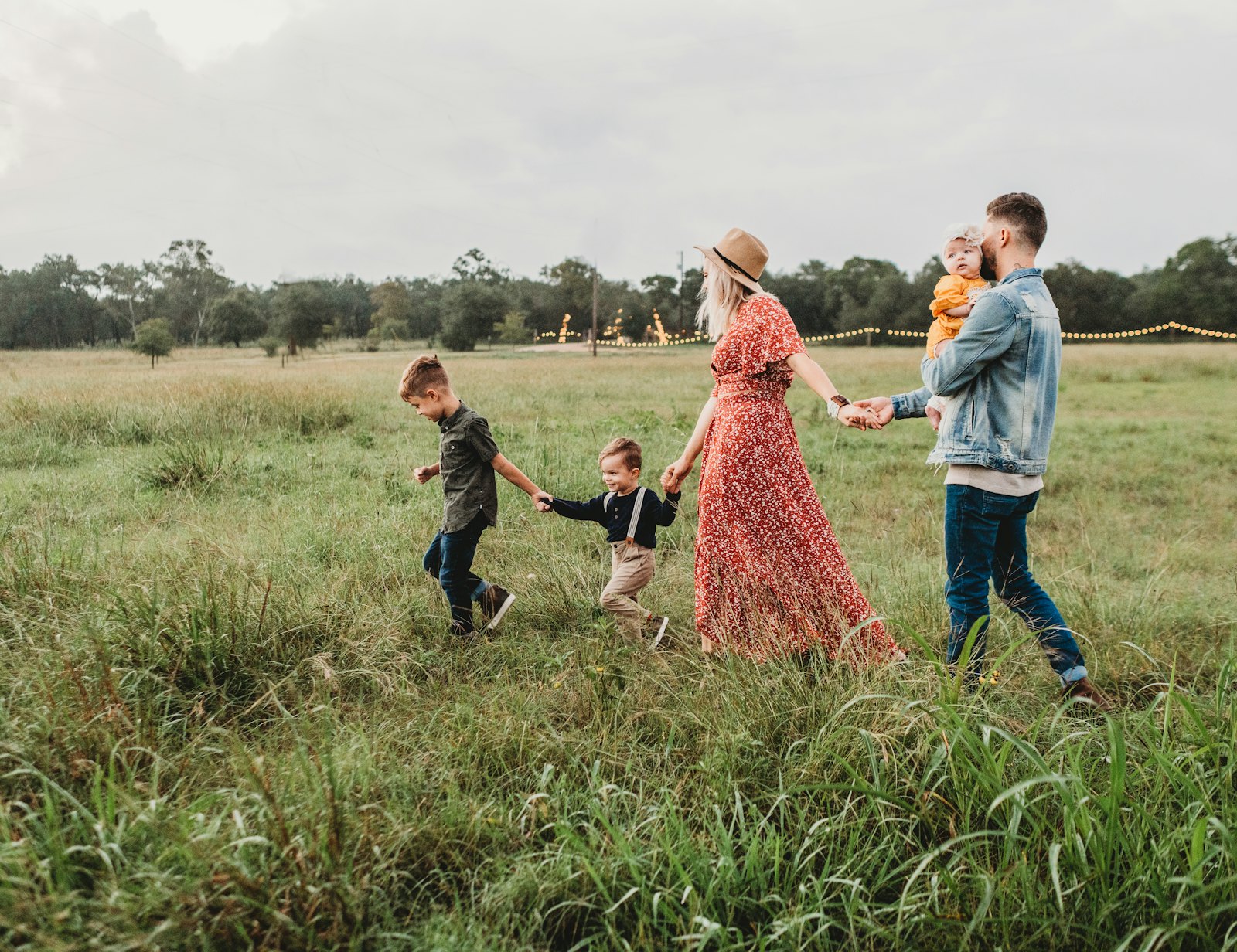 Parents walking hand in hand with their toddler through a sunny meadow
