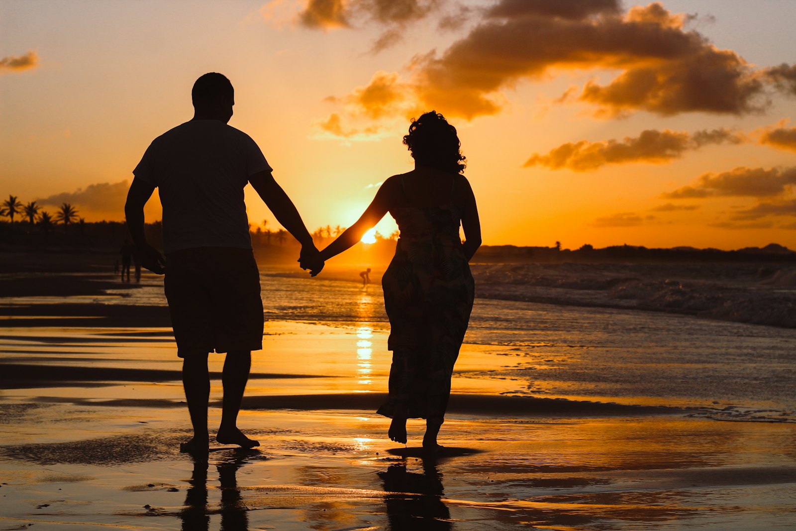 A couple standing at the water’s edge at golden hour