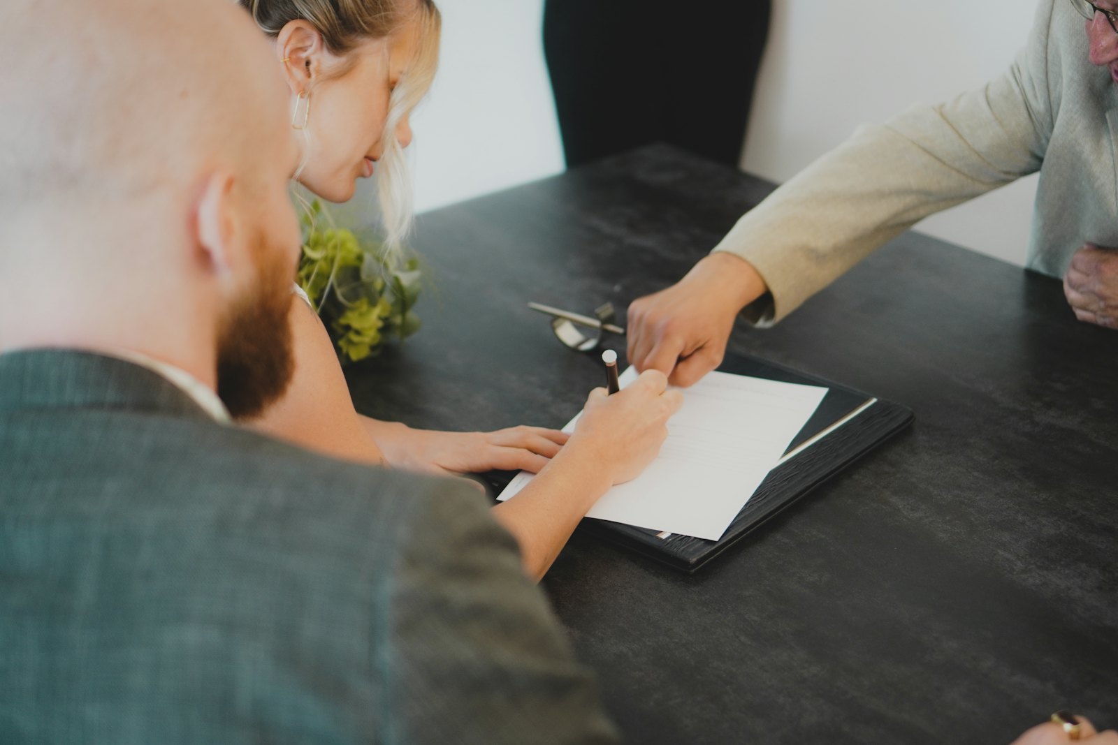 A couple signing paperwork together at a desk