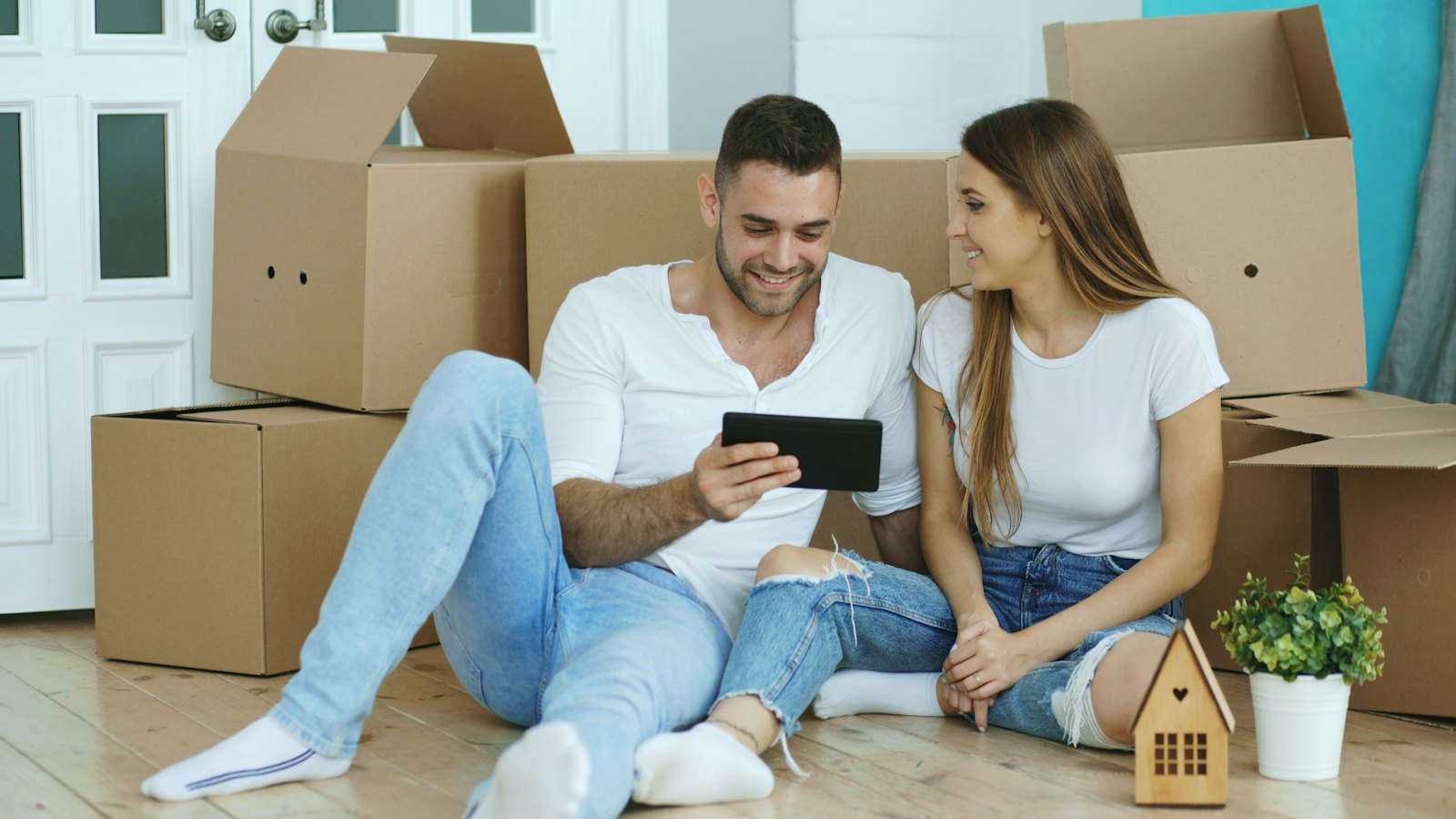 A couple looking at a tablet together, surrounded by moving boxes