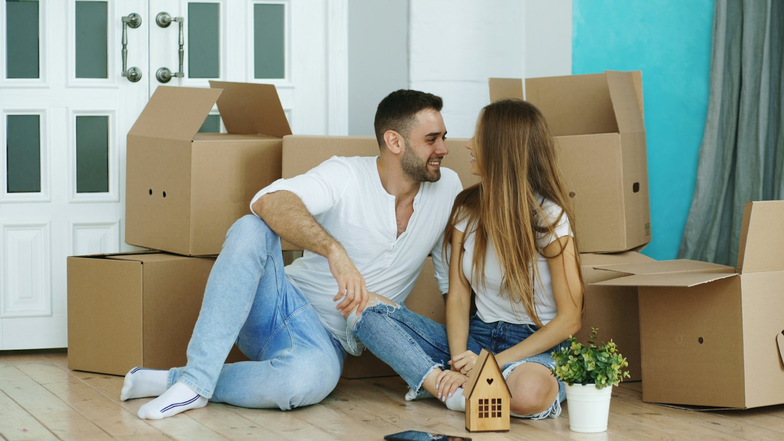 A couple sitting on the floor among moving boxes after a move